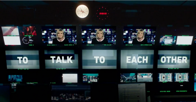 Photo from within an ITV news control room. There are lots of different TV screens in view. A female news reader appears on three screens. The words 'To Talk To Each Other' feature on five other screens.